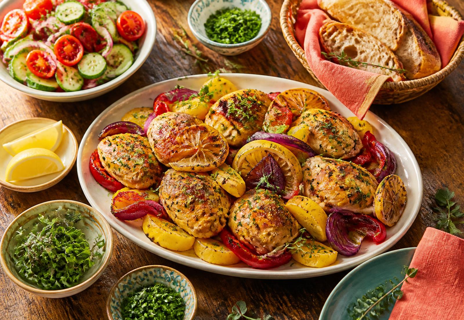 Golden herb chicken with roasted peppers, potatoes and lemon served with a fresh tomato cucumber salad